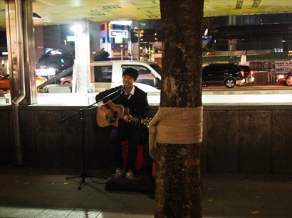 弘大地鐵站旁有位青年在唱歌！他的聲線真的不差，吸引很多人聽！很棒！