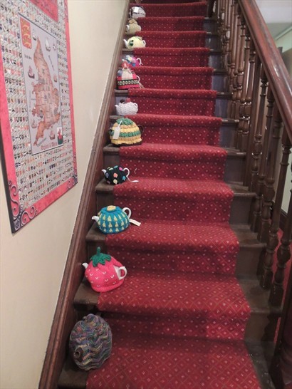 樓梯上滿佈穿上靚靚外衣，整粧待售的 Tea Cosys 