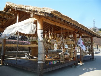 韓國村廣場正中央放左呢個木棚，木棚旁展示好多古代藤或草製用具，包括拖鞋。