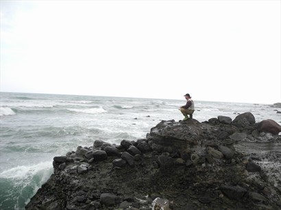 面對激浪，礁石上處之泰然的釣魚翁。